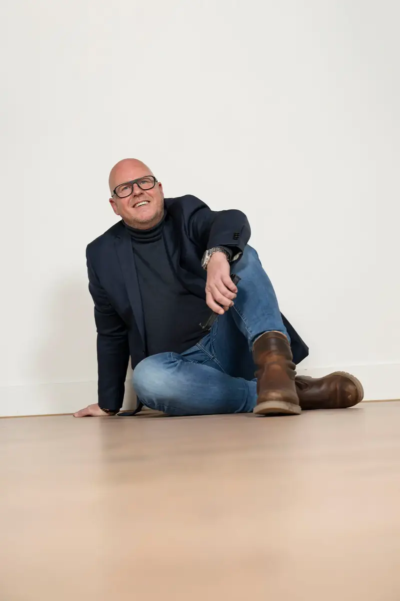 Erwin Schaafsma zit ontspannen op de vloer van een lege witte kamer